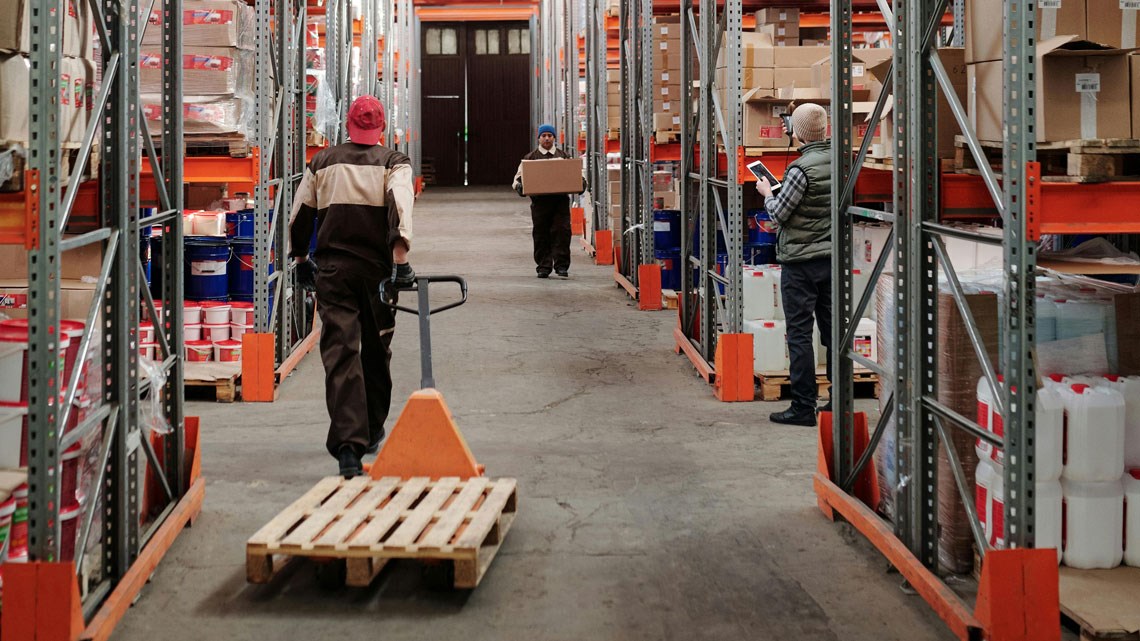 man pulling flatbed truck in warehouse