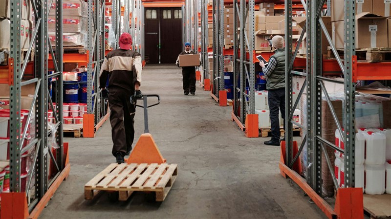 man pulling flatbed truck in warehouse