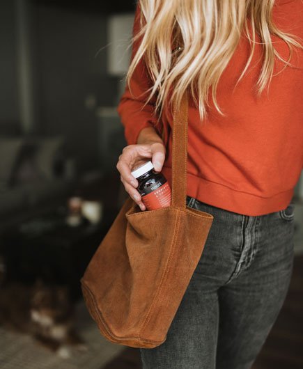 woman putting jar of supplements into bag